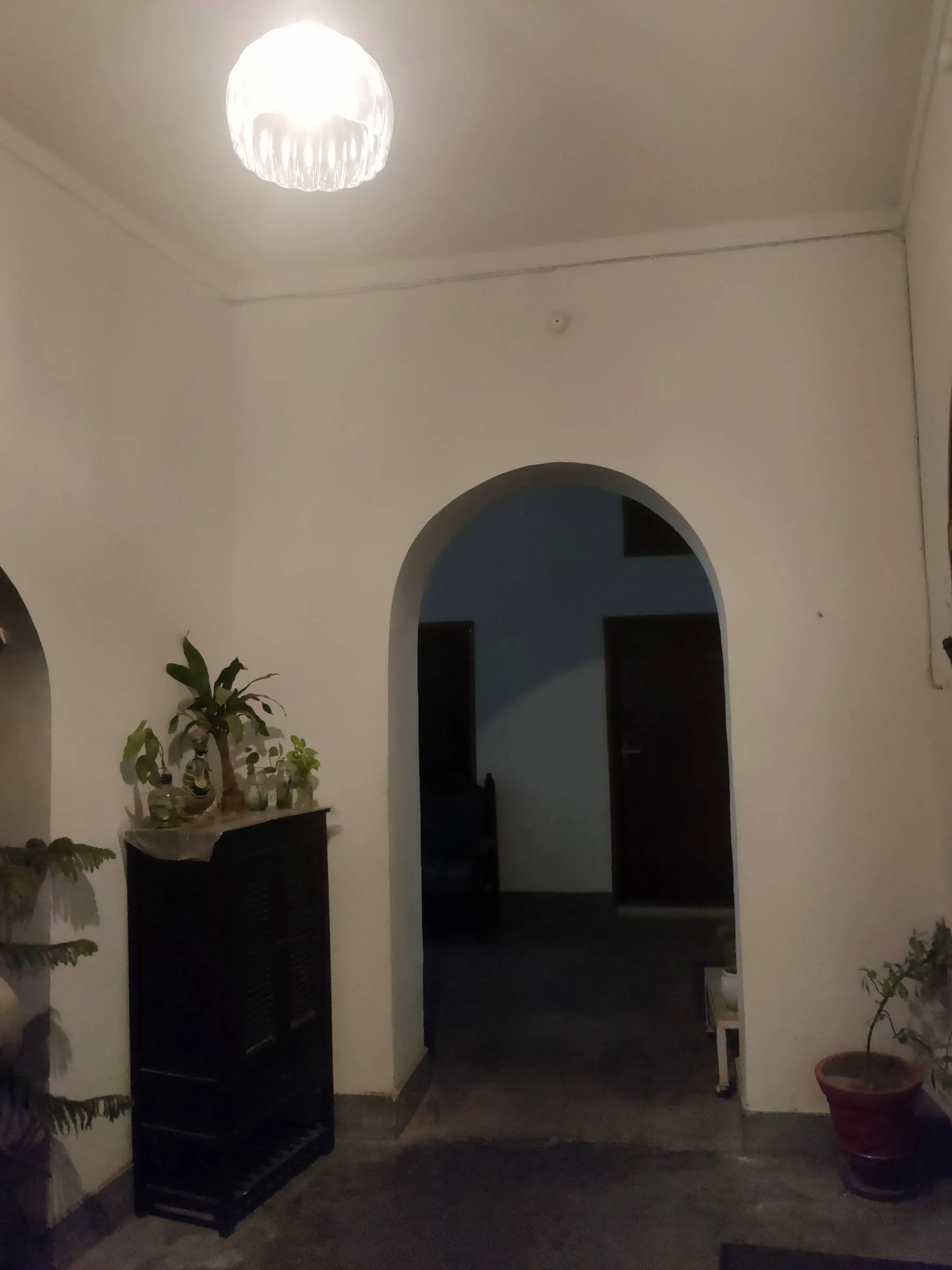 An arched inner passage of the house at night, a chandelier lighting the whitewashed vault