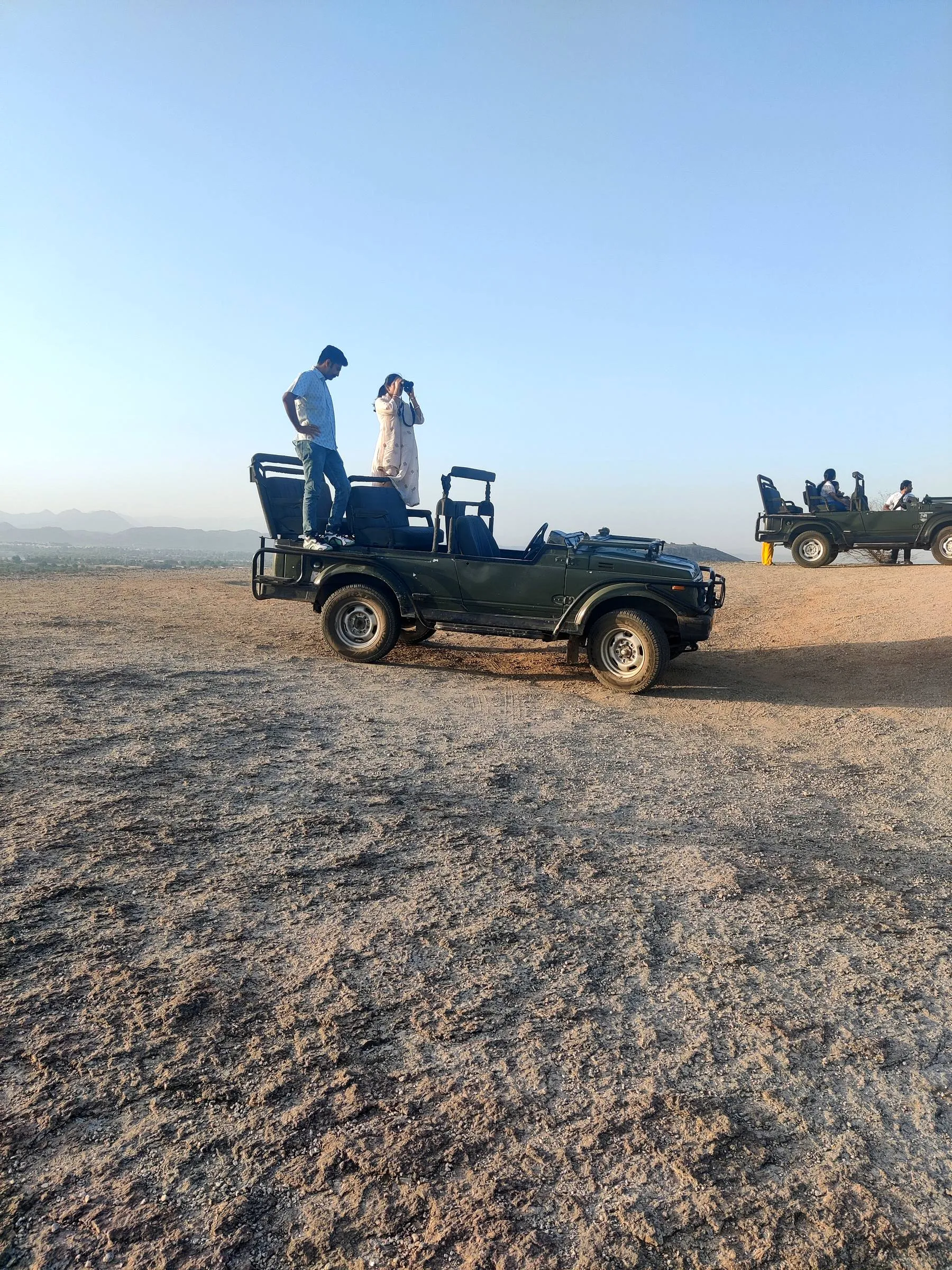 Two open safari vehicles on a bare granite plateau near Jawai, minutes after sunrise