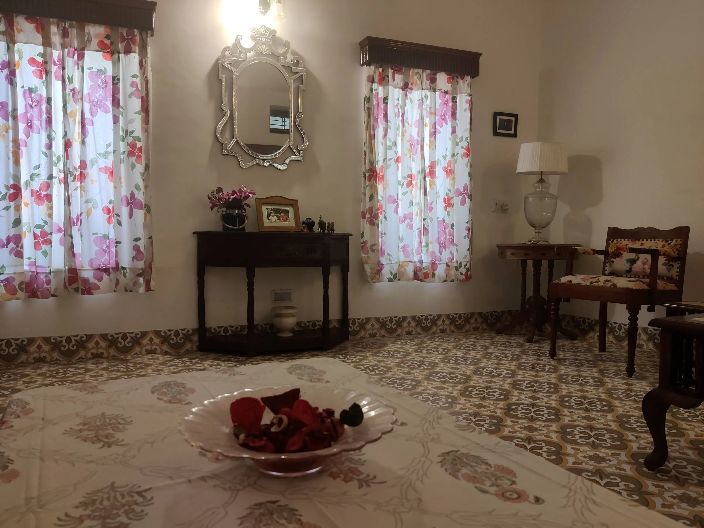 The sitting room seen from the doorway, carved settees and a low table on the patterned tiled floor