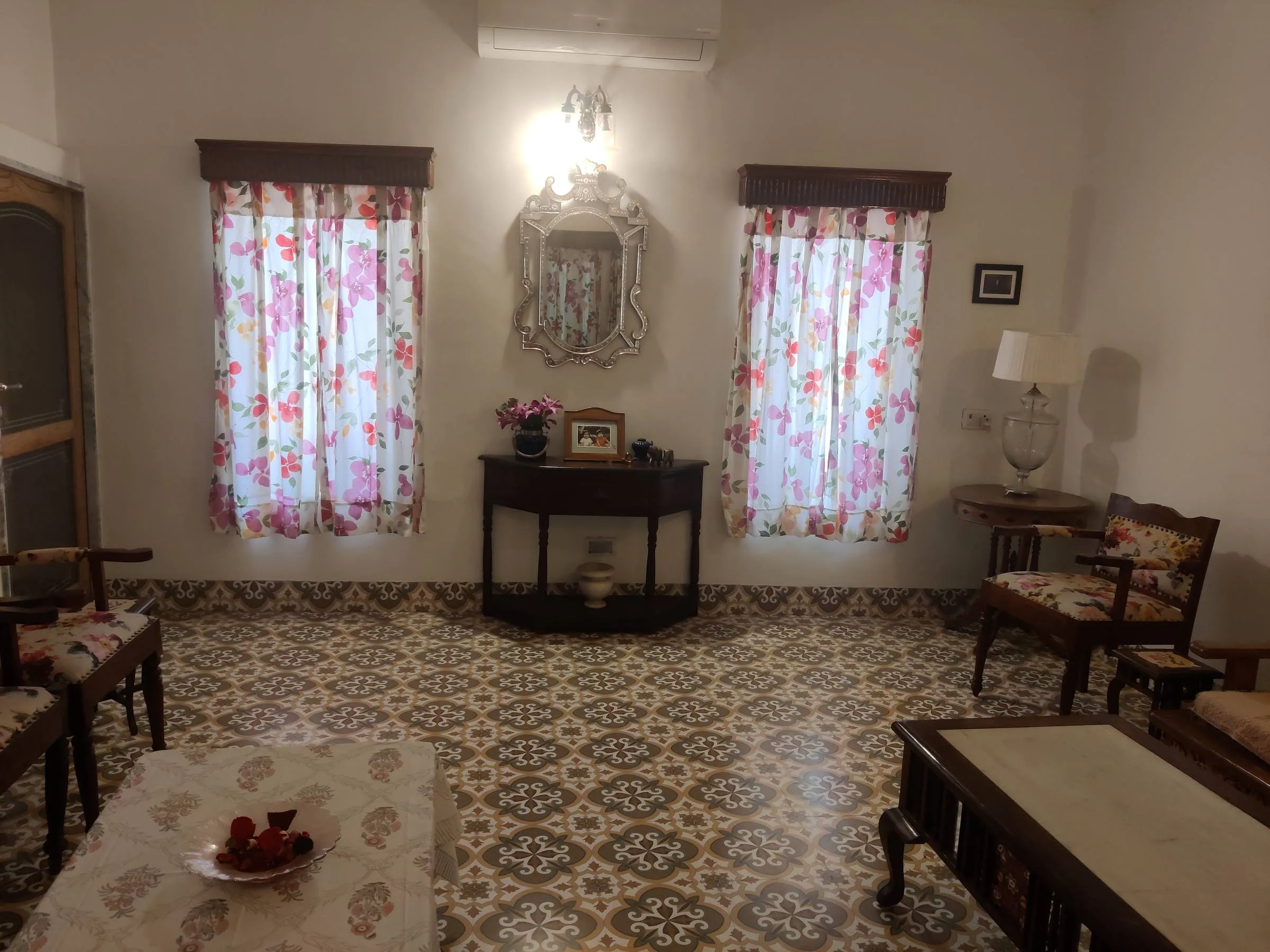 The sitting room at Rawla Bankli — a patterned encaustic-tile floor running between carved settees, low tables and a mirrored console
