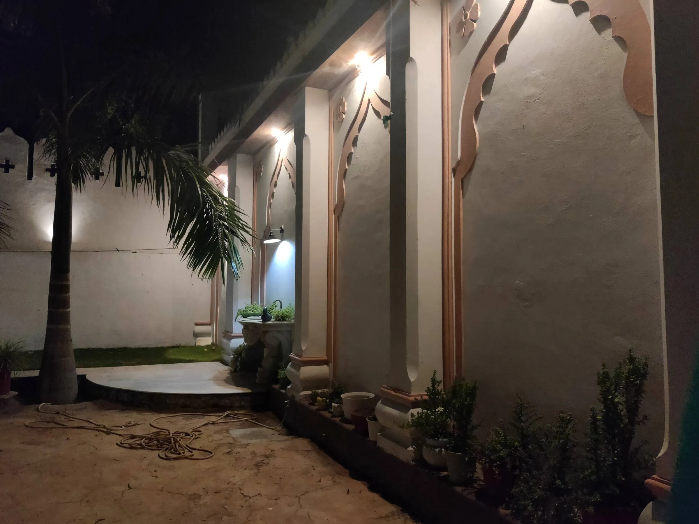 The veranda colonnade at night, its cusped arches and pink scalloped trim picked out by downlights